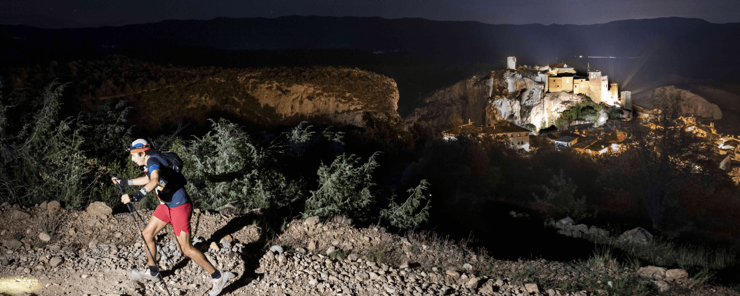 Fotografía de señor andando por camino de noche, en el fondo se ve el pueblo de Alquézar. UTGS
